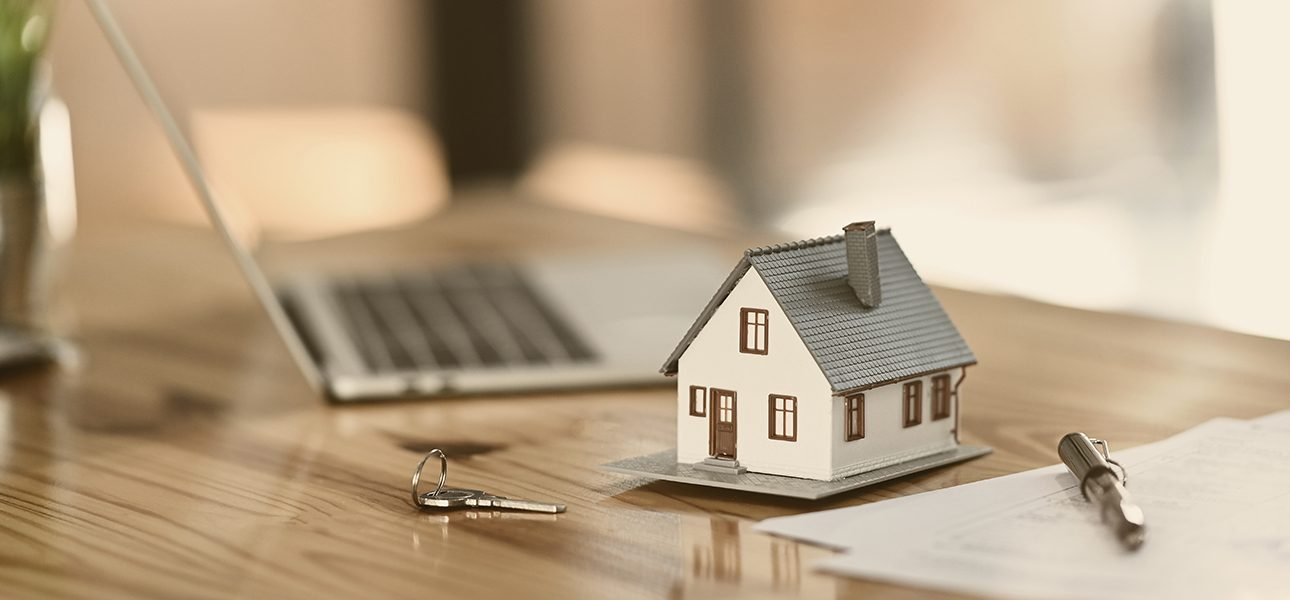 House model on sale keys on the rental agreement or the buy home contracts with the estate property background.